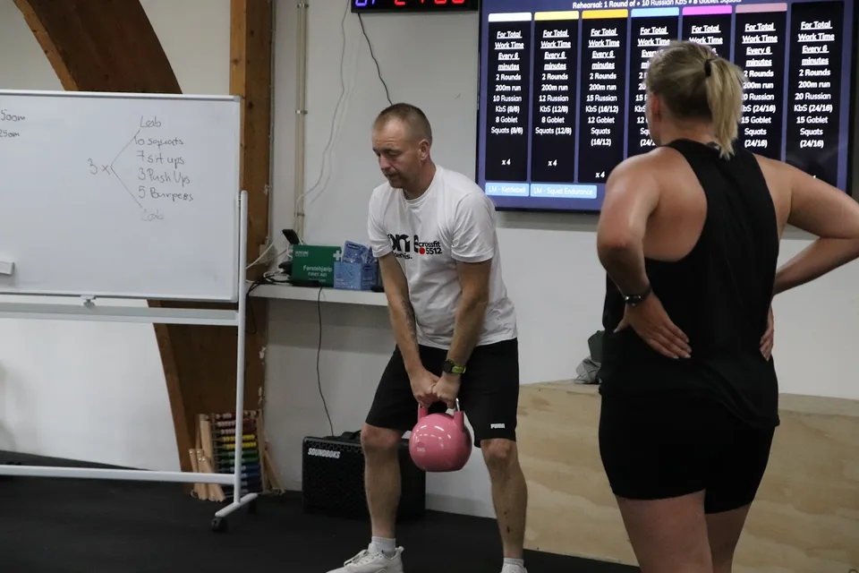 Personlig træner viser kettlebell-teknik til en kvinde hos Box One i Roskilde