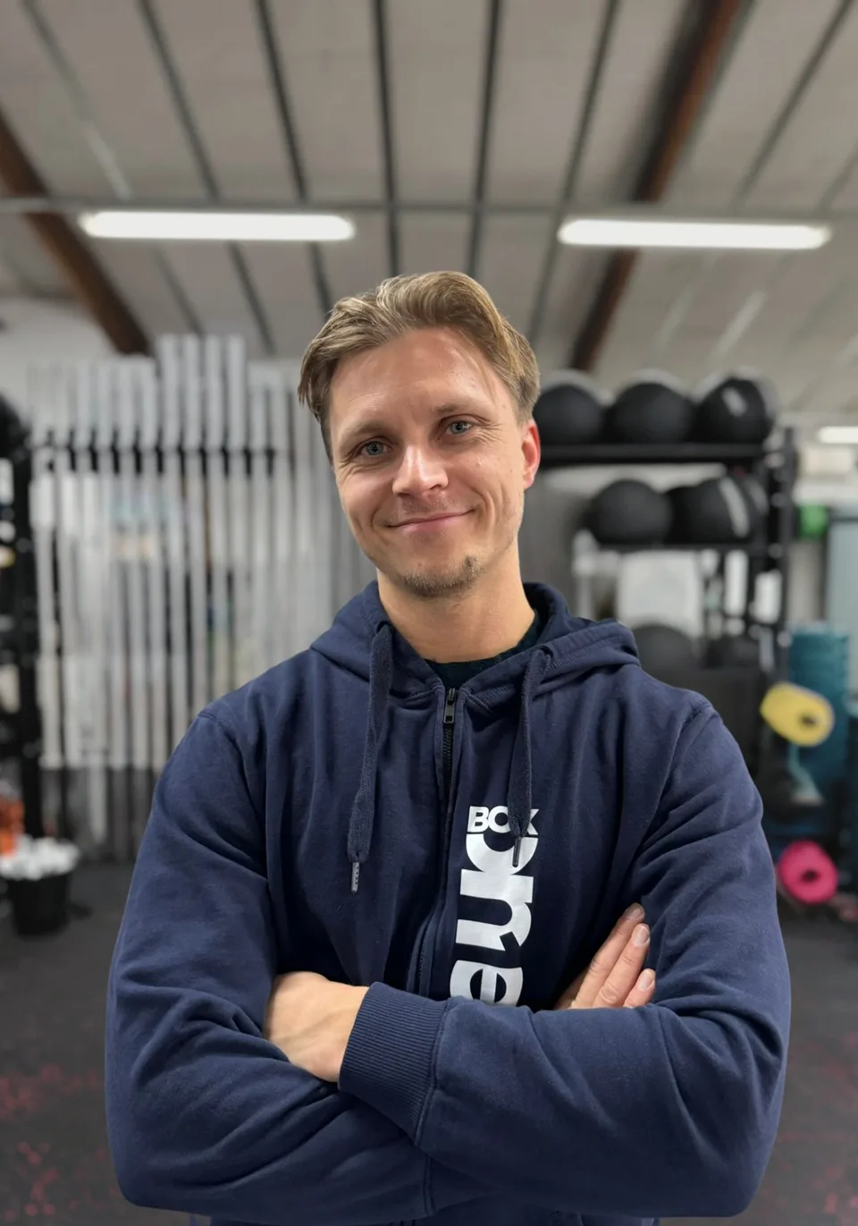 Tobias Jensen, personlig træner hos Box One, fotograferet foran den samme grå baggrund som resten af holdet.