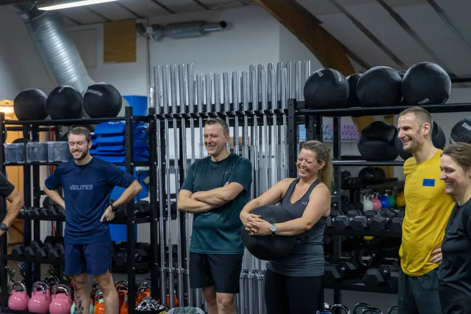 En gruppe medlemmer smiler og lytter under en introduktion i Box One.
