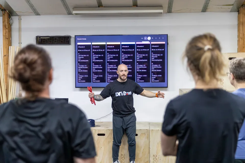 En coach giver instruktioner til et hold foran træningstavlen i Box One.
